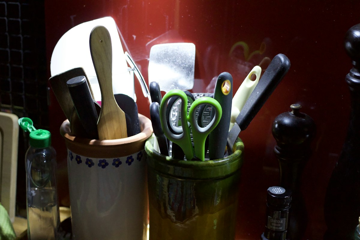 Kitchen utensils including spoons, knives, and scissors in containers