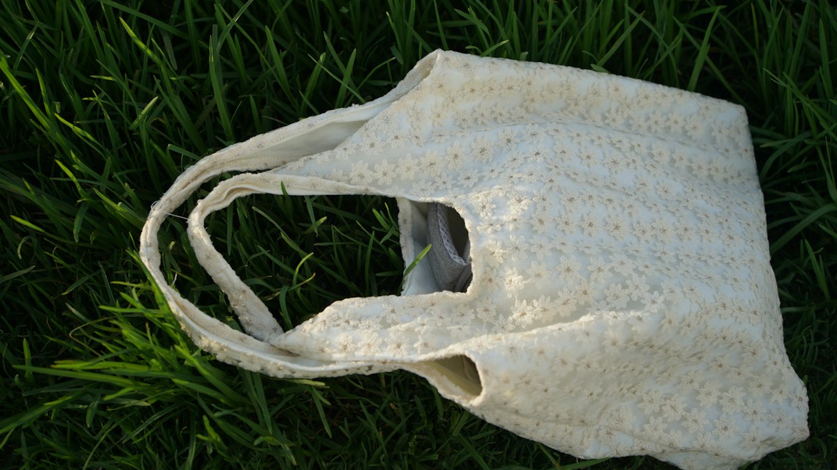 A white reusable shopping bag on green grass