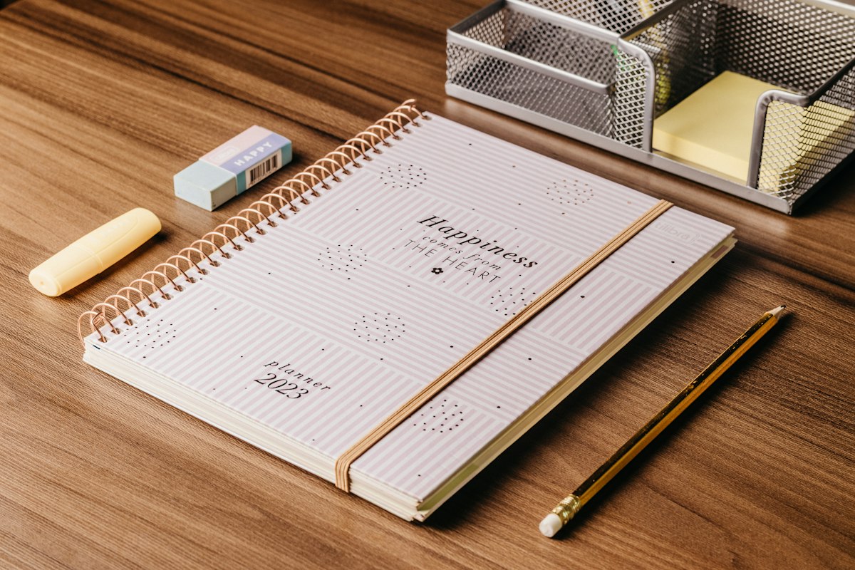 a desk with a notebook, pen, and pencil on it