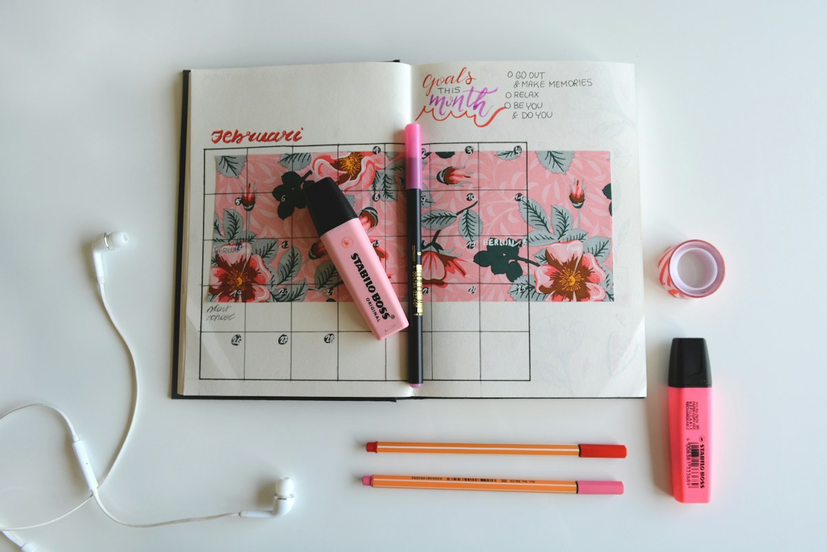 An open calendar notebook surrounded by colorful markers